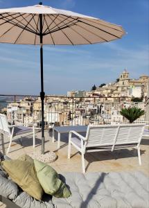 a patio with an umbrella and two chairs and a table at Mineo Townhouse with incredible views of Mt Etna in Mineo