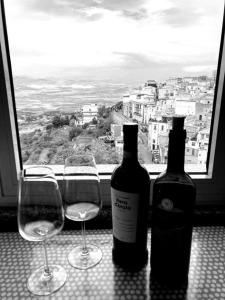 two glasses and a bottle of wine sitting next to a window at Mineo Townhouse with incredible views of Mt Etna in Mineo