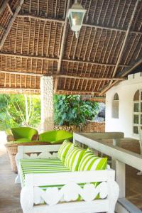 un patio con bancos verdes y blancos bajo un techo de paja en African Funhouse Mtwapa, Creek View, Jacuzzi, Table Tennis & more, en Mtwapa