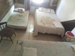 ein kleines Zimmer mit 2 Betten und einem Stuhl in der Unterkunft Casa dos corais in Vila Velha