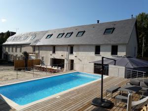 a house with a swimming pool in front of it at Au jardin de Capucine in Bricqueville-sur-Mer