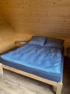a bed in a wooden room with a blue blanket at Domek Bartoszylas z sauną i balią in Bartoszylas