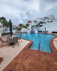 einen Pool mit einem Tisch, Stühlen und Gebäuden in der Unterkunft Beautiful Villa at The Rio Mar Beach Resort in Rio Grande