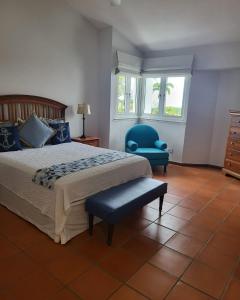 a bedroom with a bed and a blue chair at Beautiful Villa at The Rio Mar Beach Resort in Rio Grande