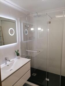 La salle de bains est pourvue d'un lavabo et d'une douche en verre. dans l'établissement Caniço Ocean Getaway, à Caniço