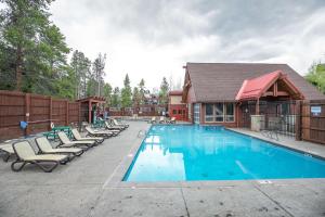 a swimming pool with lounge chairs and a house at Trails End Alpine Dream Condo: Ski In/Out, Walk to Town in Breckenridge