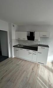 eine leere Küche mit weißen Schränken und Holzboden in der Unterkunft Modernes 2 Zimmer Appartment in Göttingen