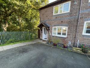 a brick house with a white door and a driveway at Riverside 2 Bedroom Townhouse with Car Charger in Abergavenny