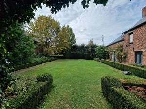 un gran patio con setos y una casa de ladrillo en Le domaine de la Rhonelle en Villers-Pol