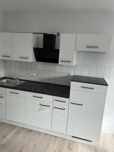 eine Küche mit weißen Schränken und einer schwarzen Arbeitsplatte in der Unterkunft Modernes 2 Zimmer Appartment in Göttingen