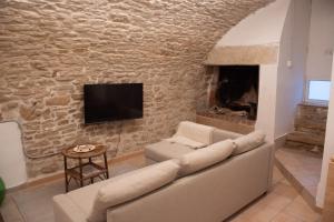 sala de estar con sofá y pared de piedra en La casa del fico Suite, en Terlizzi