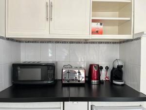 a kitchen with a black counter top with a microwave at Causey Maisonette in Hastings