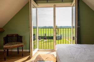 a bedroom with a large window with a view of a yard at Vakantieverblijf Weidezicht in Dorst
