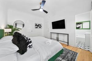 een witte slaapkamer met een bed en een flatscreen-tv bij Beverly Hills Stylish & Central 1 BR Apt + Parking in Los Angeles