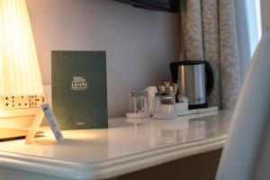 Hotel Du Lac & SPA في بيلاجيو: طاولة مع آلة صنع القهوة وكتاب عليها
