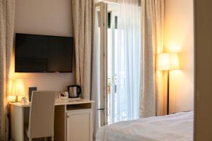 a hotel room with a bed and a desk and a television at Hotel Du Lac & SPA in Bellagio