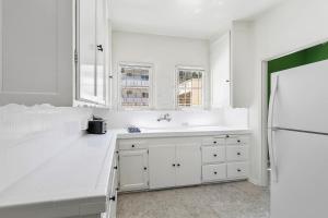 a white kitchen with a sink and a refrigerator at Beverly Hills Stylish & Central 1 BR Apt + Parking in Los Angeles