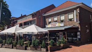 a building with tables and umbrellas in front of it at Franziskaner am Markt in Löningen