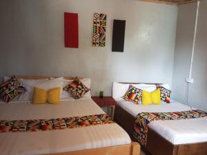 two beds with colorful pillows in a room at The Nido Hotel in Meru