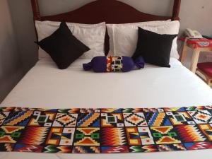 a bed with a colorful comforter and pillows on it at The Nido Hotel in Meru