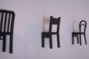 Trois chaises noires sont placées sur un mur blanc dans l'établissement Giustiniani Apartments, à Trévise