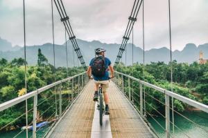 Ein Mann, der mit dem Fahrrad über eine Brücke fährt. in der Unterkunft Phong Nha Dawn Home in Phong Nha