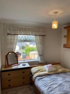 1 dormitorio con cama, espejo y ventana en EEJs Cozy 2-Bedroom Apartment in Nailsea en Nailsea