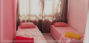 2 łóżka pojedyncze w pokoju z różowymi ścianami w obiekcie SAXÔNiA HOTEL w mieście Balneário Camboriú
