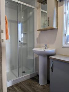 a bathroom with a glass shower and a sink at Beautiful Pet Friendly Southerness Caravan With Sea View & Decking Area in Mainsriddle