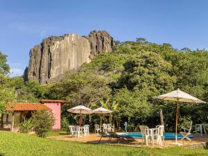 a pool with chairs and umbrellas in front of a mountain at Pousada Grande Pedreira in Serra do Cipo