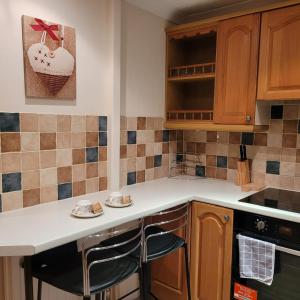 kuchnia z drewnianymi szafkami i blatem ze stołkami w obiekcie EEJs Cozy 2-Bedroom Apartment in Nailsea w mieście Nailsea