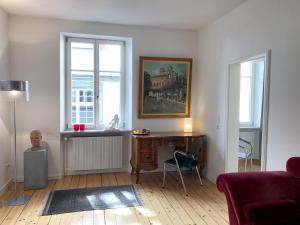 ein Wohnzimmer mit einem Schreibtisch und 2 Fenstern in der Unterkunft Ferienwohnung Insel-Residenz 1 in Lindau