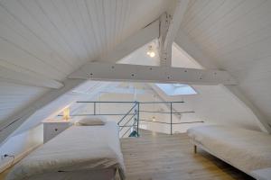 a attic bedroom with two beds and a staircase at Le Harmony - Appart'Escale in Saint-Nazaire