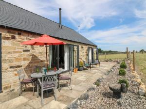 a stone cottage with a table and chairs and an umbrella at The Cottage in Chesterfield