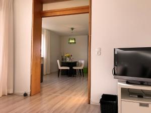 Una sala de estar con televisión y una mesa de comedor. en Ferienwohnung Alina- Penthouse Wohnung mit atemberaubendem Blick zum Bodensee, en Kressbronn am Bodensee