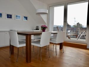een eetkamer met een houten tafel en witte stoelen bij Ferienwohnung 180 Grad im 2 OG mit Panoramafenster See und Bergblick in Wasserburg +17 foto's