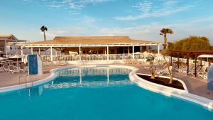ein großer Pool mit einem Gebäude im Hintergrund in der Unterkunft Caleta Dorada in Caleta de Fuste