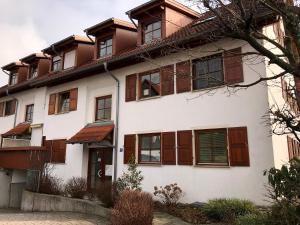 ein weißes Haus mit braunen Fenstern und einem Baum in der Unterkunft Ferienwohnung Vera in Lindau-Bodolz