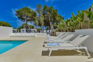 a row of white lounge chairs next to a swimming pool at LA CALITA- By Almarina Villas in Moraira