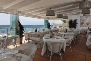 a restaurant with white tables and chairs and the ocean at LA CALITA- By Almarina Villas in Moraira