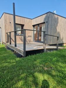 a house with a deck on a grass field at L'écolodge de Laeti in Lunéville