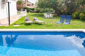 een zwembad met 2 stoelen en een tafel en stoelen bij Villa Nuis L'Estartit. Piscina y jardín privados. Ideal para familias in Torroella de Montgrí