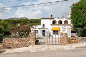een wit huis met een stenen hek bij Villa Nuis L'Estartit. Piscina y jardín privados. Ideal para familias in Torroella de Montgrí