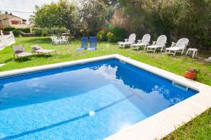 een blauw zwembad met stoelen en een tuin bij Villa Nuis L'Estartit. Piscina y jardín privados. Ideal para familias in Torroella de Montgrí