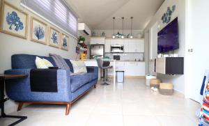 a living room with a blue couch and a kitchen at Casa Arrecife 28 in Cabo Rojo