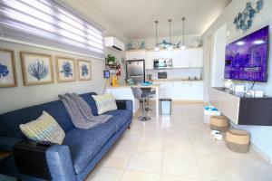 a living room with a blue couch and a kitchen at Casa Arrecife 28 in Cabo Rojo