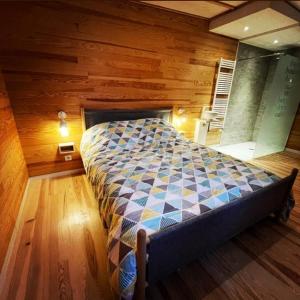 1 dormitorio con 1 cama en una habitación con paredes de madera en L'écolodge de Laeti, en Lunéville