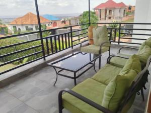 einen Balkon mit 2 Stühlen und einem Couchtisch darauf in der Unterkunft Kagarama Residential House: in Kigali