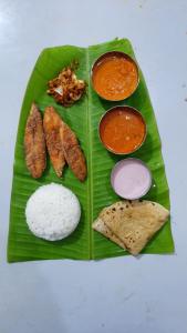 a plate of food with rice and meat on a banana leaf at Costel in Malvan