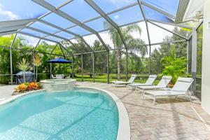 a swimming pool in a glass house with a patio at Modern home w screened pool, hot tub, & comm amenities! in Naples